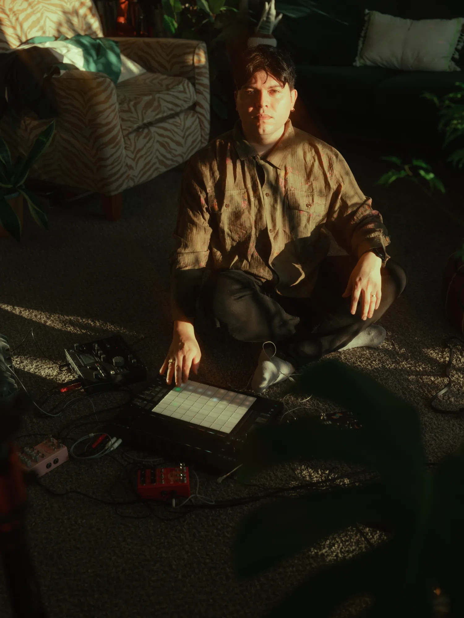 Nil Elses seated among electronic instruments in afternoon light